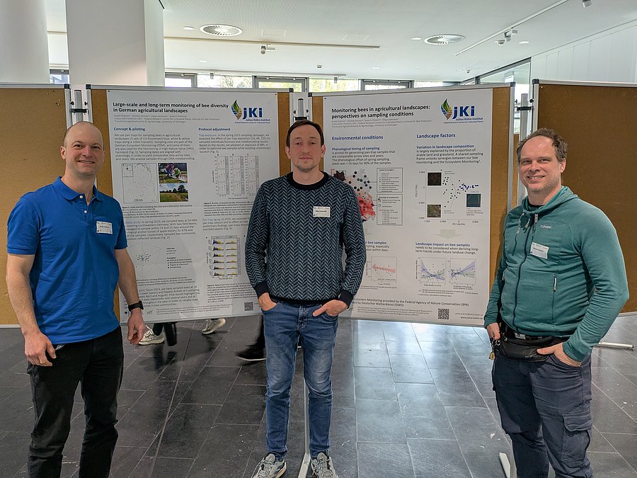 3 persons in front of 2 display boards