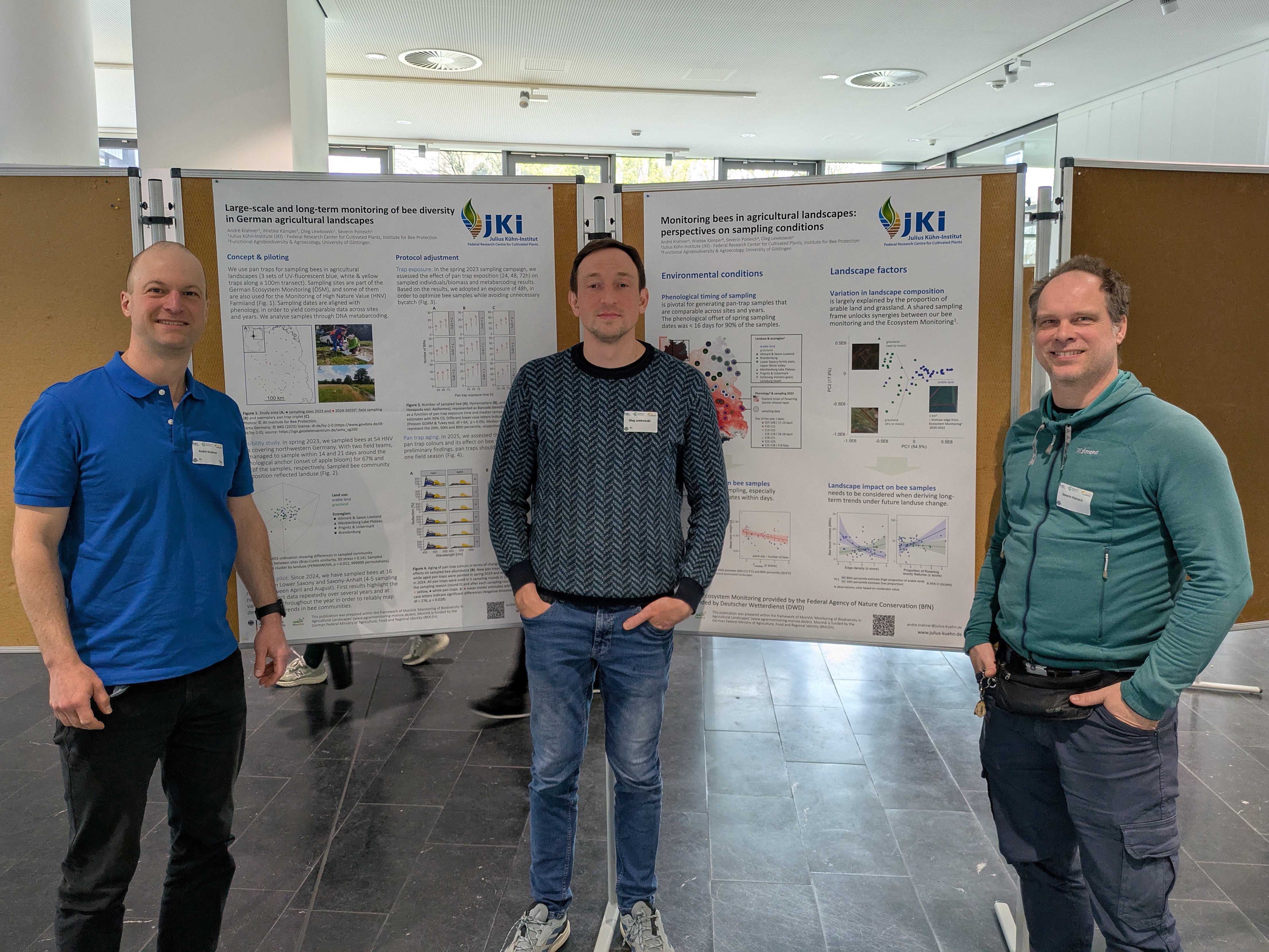 3 persons in front of 2 display boards