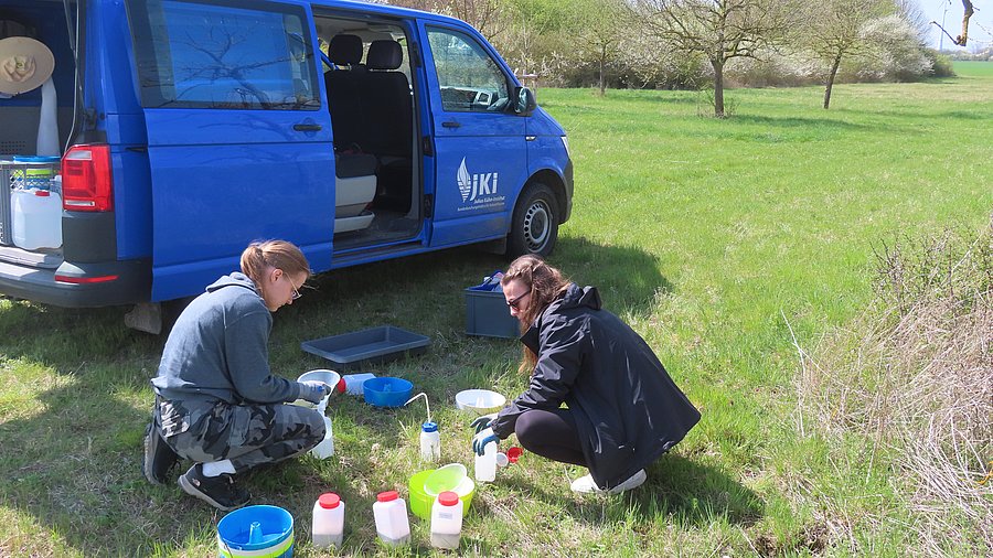 2 Personen vor Bus im Feld